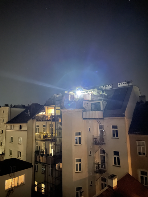 night time view of a building with a terrace on top with a strong light on